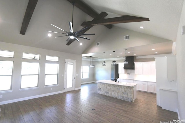 kitchen featuring dark hardwood / wood-style floors, pendant lighting, beamed ceiling, white cabinetry, and a spacious island