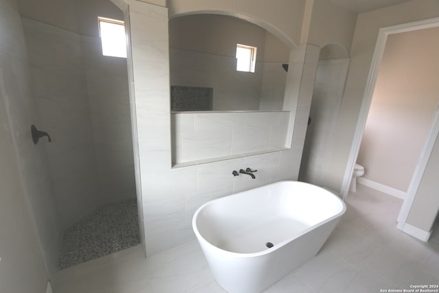 bathroom featuring a healthy amount of sunlight, tile walls, toilet, and plus walk in shower