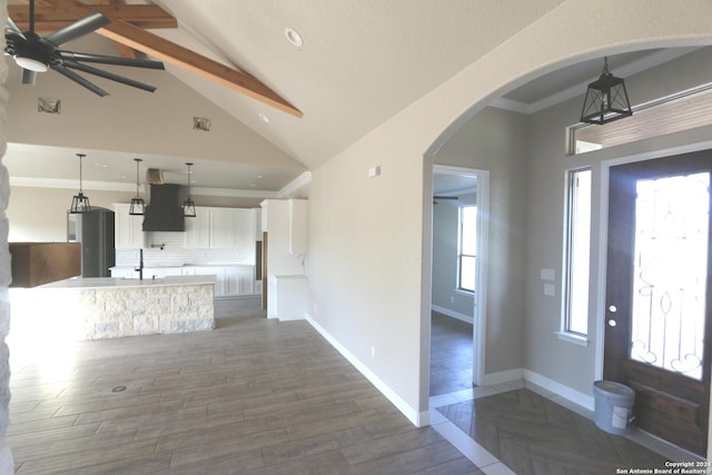 interior space featuring beamed ceiling, ornamental molding, dark wood-type flooring, and high vaulted ceiling