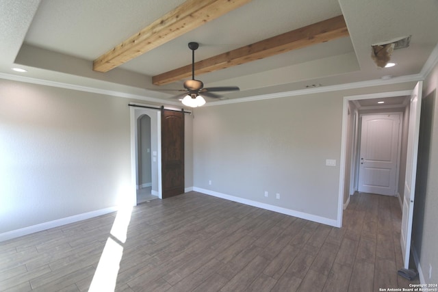 spare room with hardwood / wood-style floors, beamed ceiling, ornamental molding, ceiling fan, and a barn door