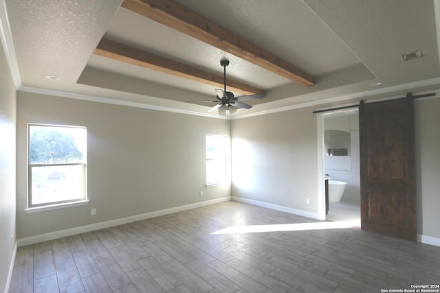 empty room featuring hardwood / wood-style flooring, ceiling fan, a raised ceiling, a barn door, and beam ceiling