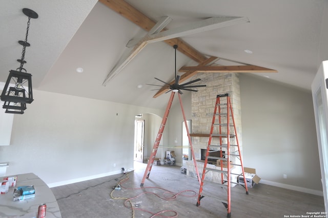 unfurnished living room with wood-type flooring, beam ceiling, high vaulted ceiling, a stone fireplace, and ceiling fan