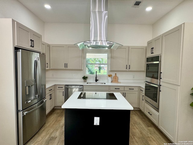 kitchen featuring light hardwood / wood-style flooring, exhaust hood, a kitchen island, stainless steel appliances, and sink