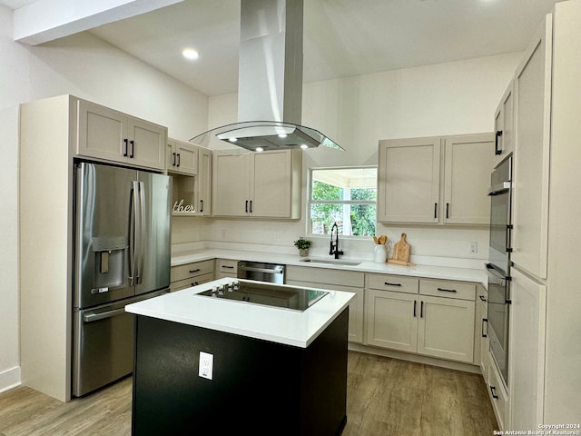 kitchen featuring light hardwood / wood-style flooring, stainless steel appliances, island range hood, sink, and a kitchen island