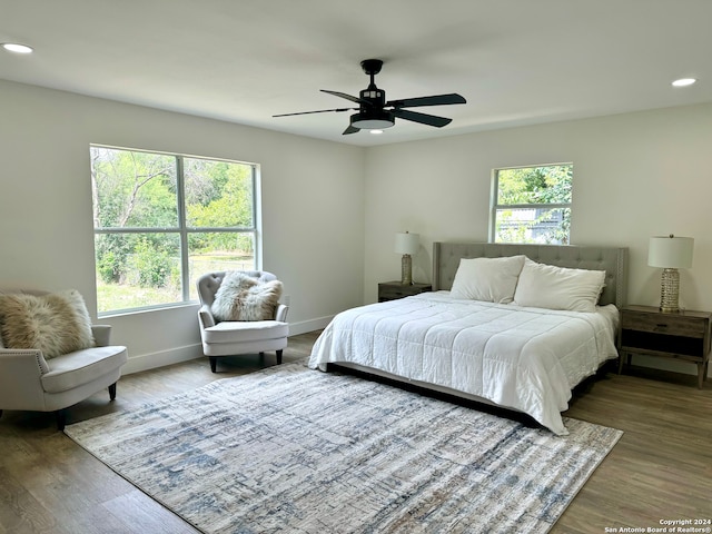 bedroom featuring ceiling fan, multiple windows, and hardwood / wood-style flooring