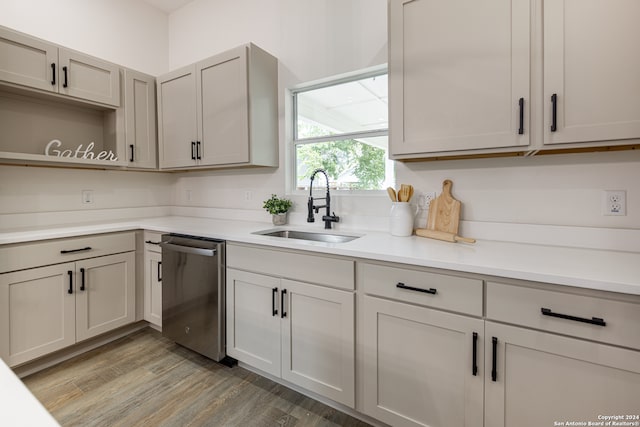 kitchen featuring sink, dishwasher, light hardwood / wood-style flooring, and gray cabinetry