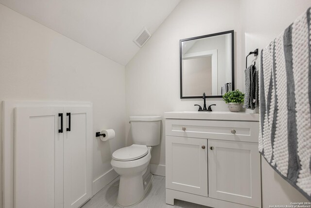 bathroom with lofted ceiling, tile patterned floors, toilet, and vanity