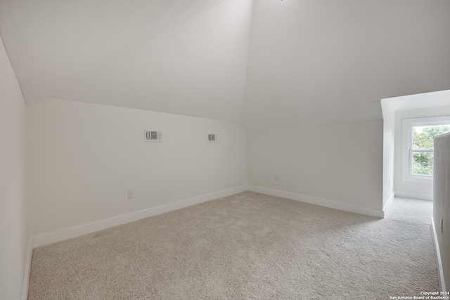 bonus room with lofted ceiling and light carpet