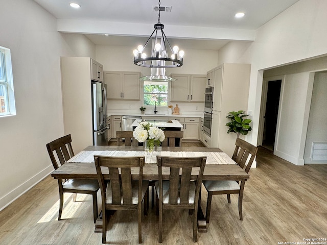 dining area with an inviting chandelier, sink, light hardwood / wood-style flooring, and beam ceiling