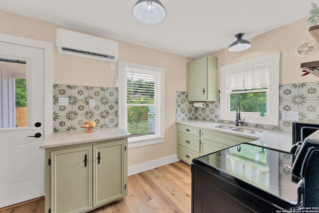 kitchen featuring a wall mounted AC, sink, light hardwood / wood-style flooring, and green cabinets