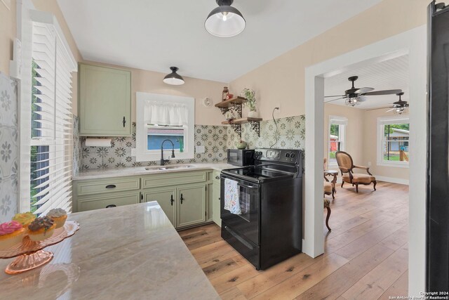 kitchen featuring electric range, light hardwood / wood-style flooring, ceiling fan, green cabinetry, and sink