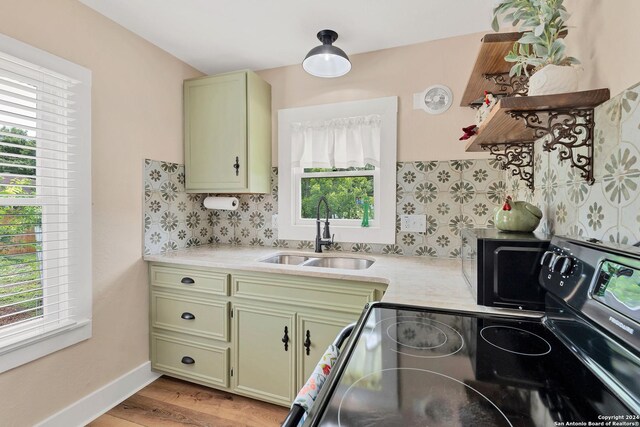 kitchen featuring stove, sink, light hardwood / wood-style flooring, and a wealth of natural light