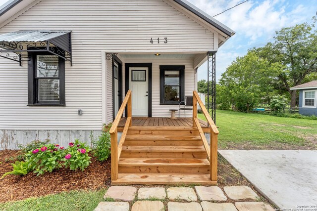 doorway to property featuring a lawn and covered porch