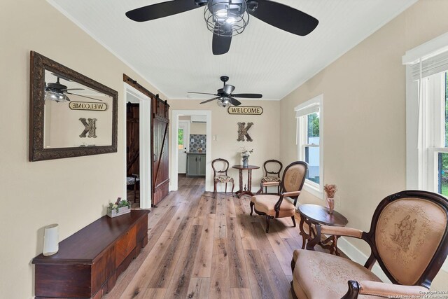 sitting room with hardwood / wood-style floors, a barn door, and ceiling fan