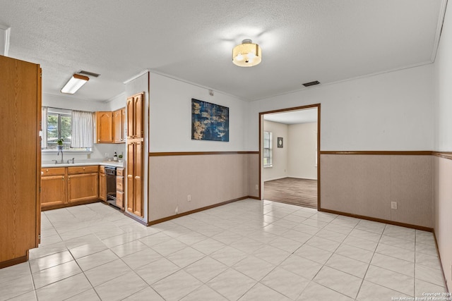 interior space featuring black dishwasher, sink, a textured ceiling, and light tile patterned floors