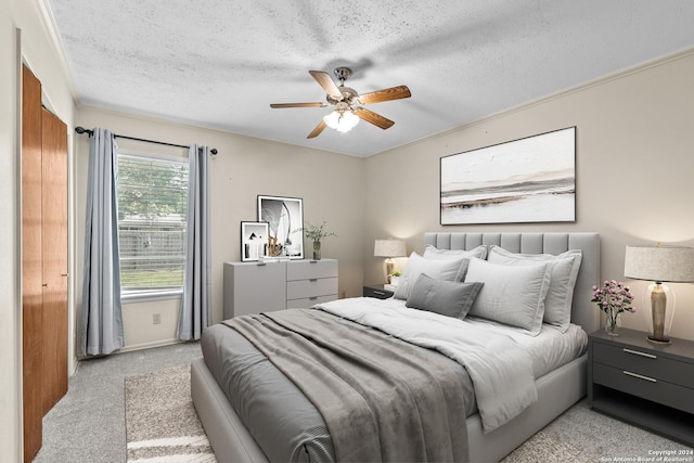 carpeted bedroom with ceiling fan and a textured ceiling