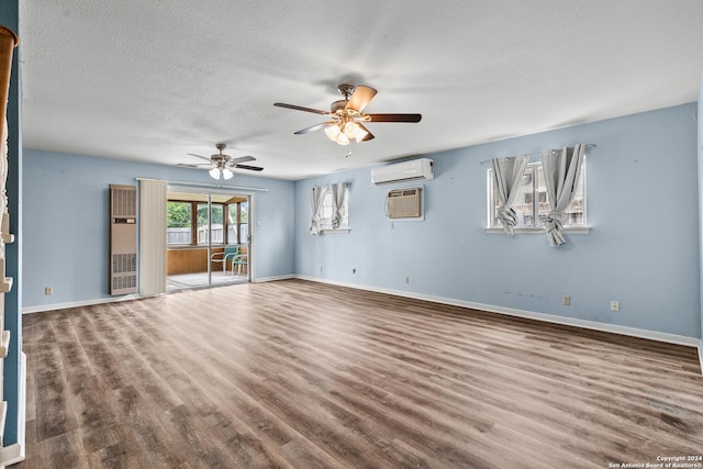 spare room with ceiling fan, hardwood / wood-style floors, a textured ceiling, and a wall unit AC