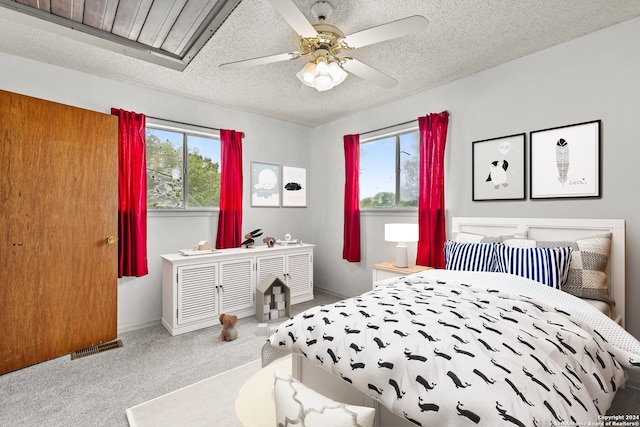 carpeted bedroom with ceiling fan and a textured ceiling