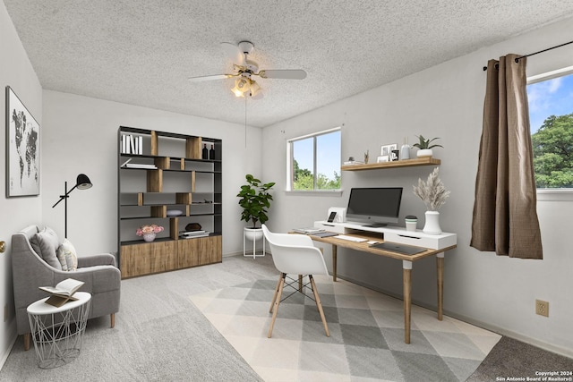 carpeted home office with ceiling fan and a textured ceiling