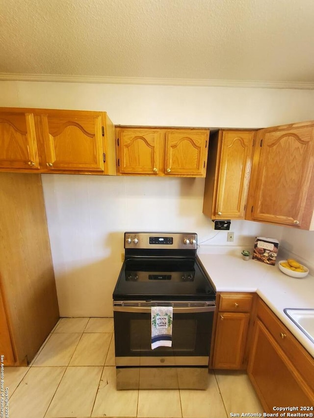 kitchen featuring light tile patterned floors, ornamental molding, stainless steel range with electric cooktop, and a textured ceiling