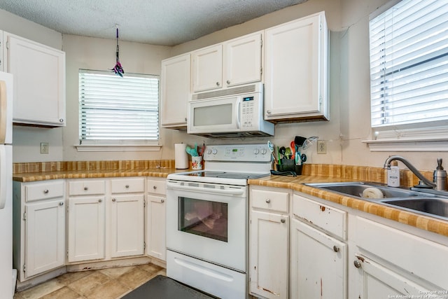 kitchen featuring sink, white appliances, a textured ceiling, and white cabinets