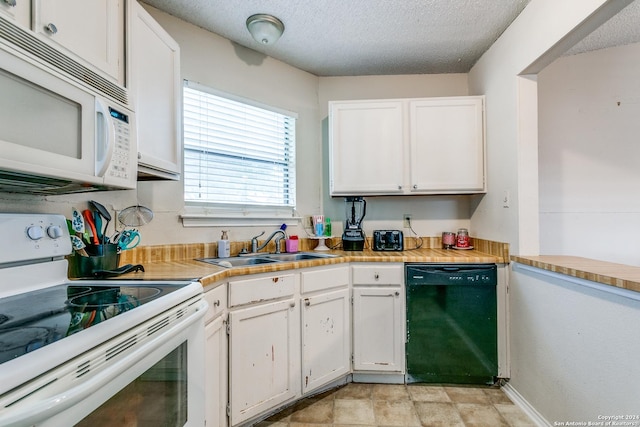 kitchen featuring white cabinetry, sink, a textured ceiling, and white appliances