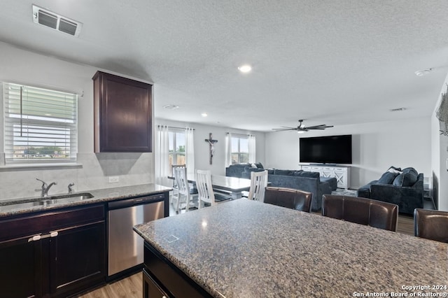 kitchen with sink, light hardwood / wood-style floors, stainless steel dishwasher, stone countertops, and ceiling fan