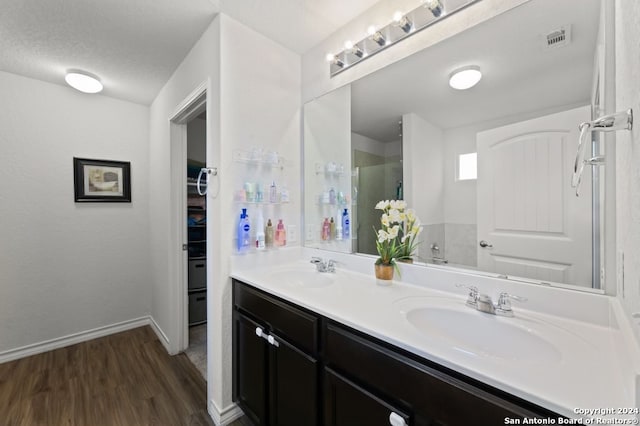 bathroom featuring wood-type flooring, a textured ceiling, and dual bowl vanity