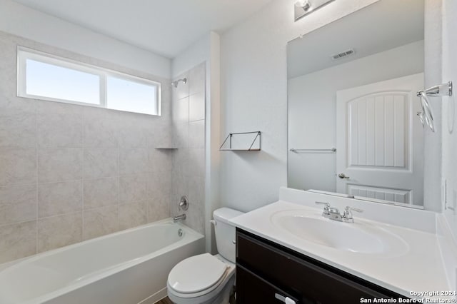 full bathroom featuring vanity, tiled shower / bath combo, and toilet