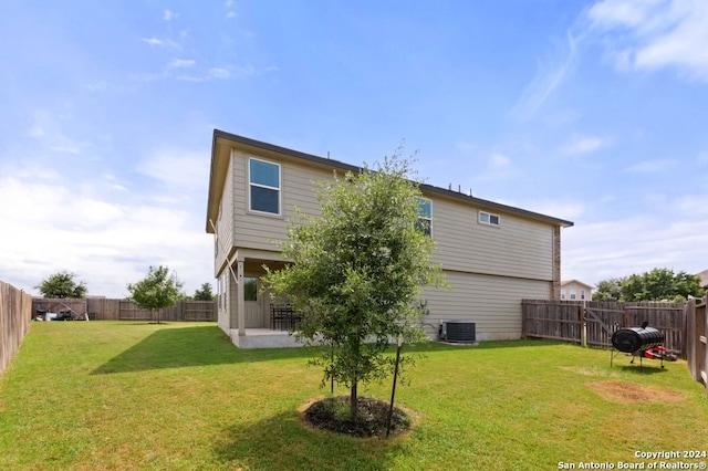 back of property with a patio area, central AC unit, and a yard