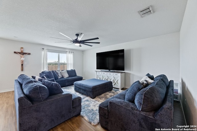 living room with a textured ceiling, ceiling fan, and hardwood / wood-style floors