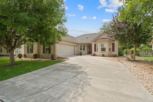 single story home with brick siding, fence, a garage, driveway, and a front lawn