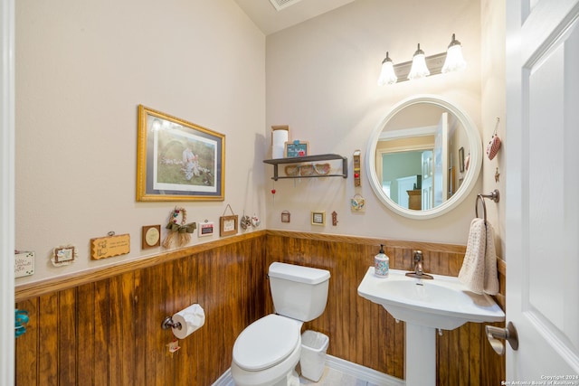 bathroom with a wainscoted wall, wood walls, and toilet