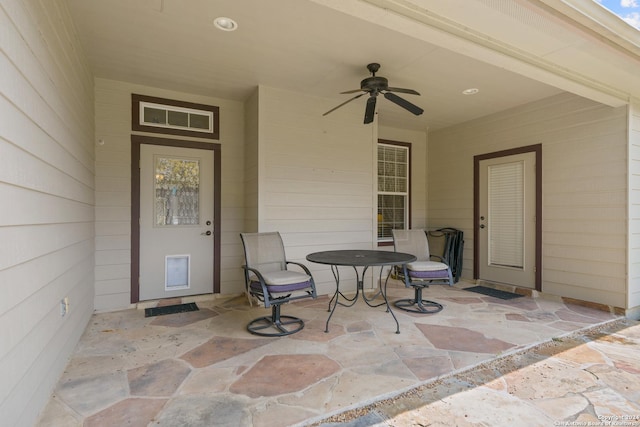 view of exterior entry with ceiling fan and a patio