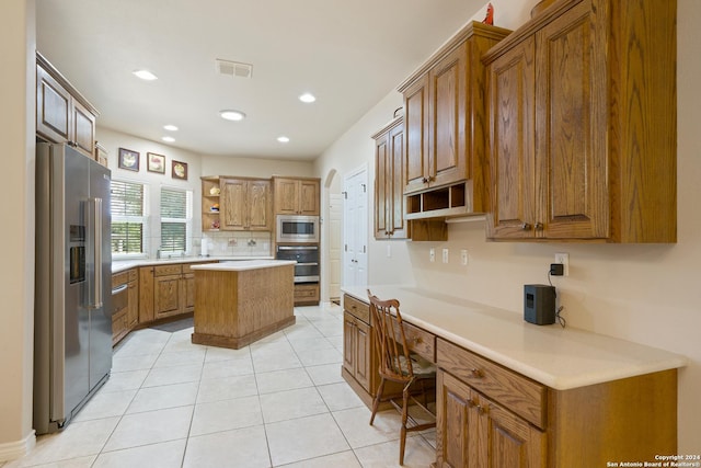 kitchen with open shelves, light countertops, appliances with stainless steel finishes, built in study area, and a kitchen island