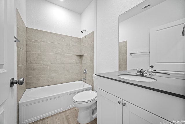 full bathroom featuring toilet, hardwood / wood-style floors, vanity, and tiled shower / bath