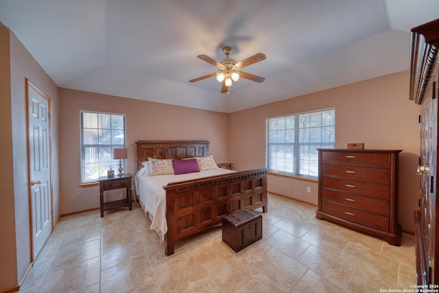 bedroom featuring multiple windows, a tray ceiling, vaulted ceiling, and ceiling fan