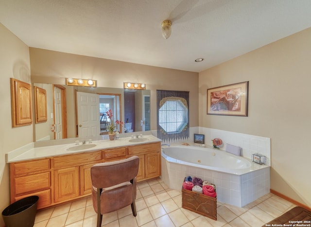 bathroom featuring tiled tub, vanity, tile patterned floors, and a textured ceiling