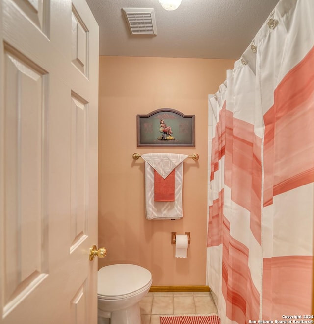 bathroom with tile patterned flooring, a textured ceiling, and toilet