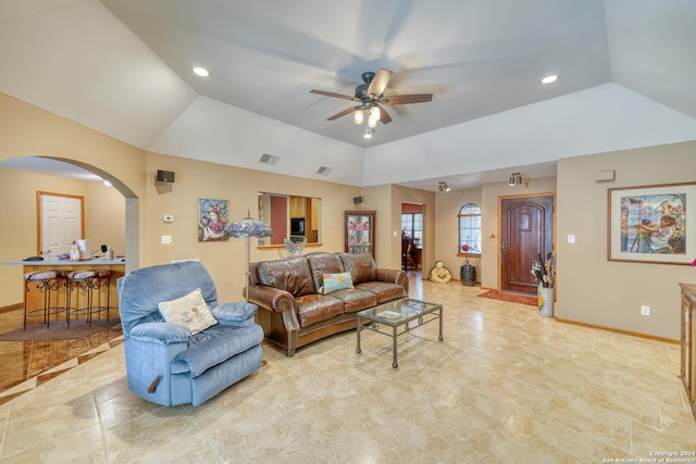 living room with a tray ceiling, vaulted ceiling, and ceiling fan