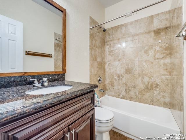 full bathroom featuring vanity, tiled shower / bath combo, and toilet