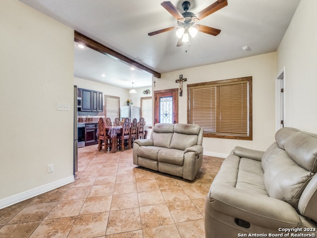 tiled living room featuring beamed ceiling and ceiling fan