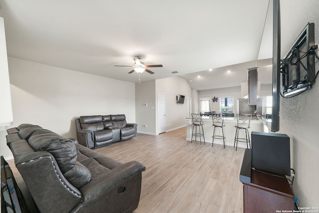 living room featuring ceiling fan, lofted ceiling, and light hardwood / wood-style floors