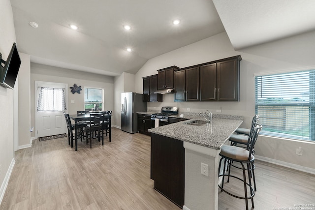 kitchen with a breakfast bar, sink, kitchen peninsula, stainless steel appliances, and light stone countertops