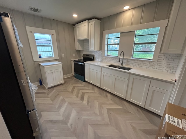 kitchen with white cabinetry, light parquet floors, stainless steel electric stove, decorative backsplash, and sink