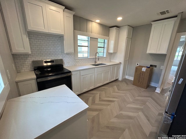 kitchen with sink, light parquet floors, electric stove, and white cabinets