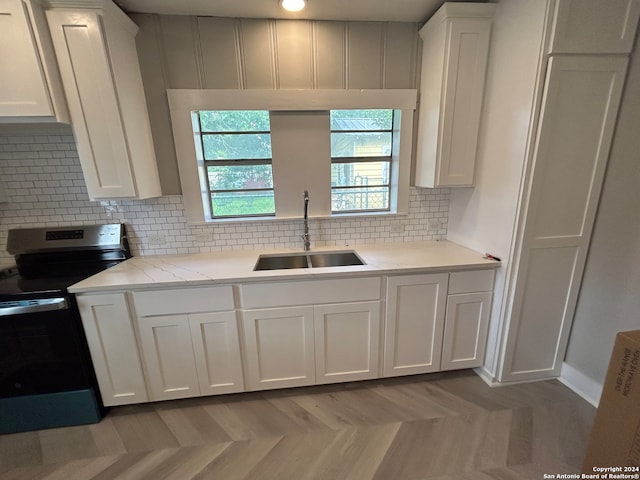 kitchen with electric range, light parquet flooring, tasteful backsplash, and sink