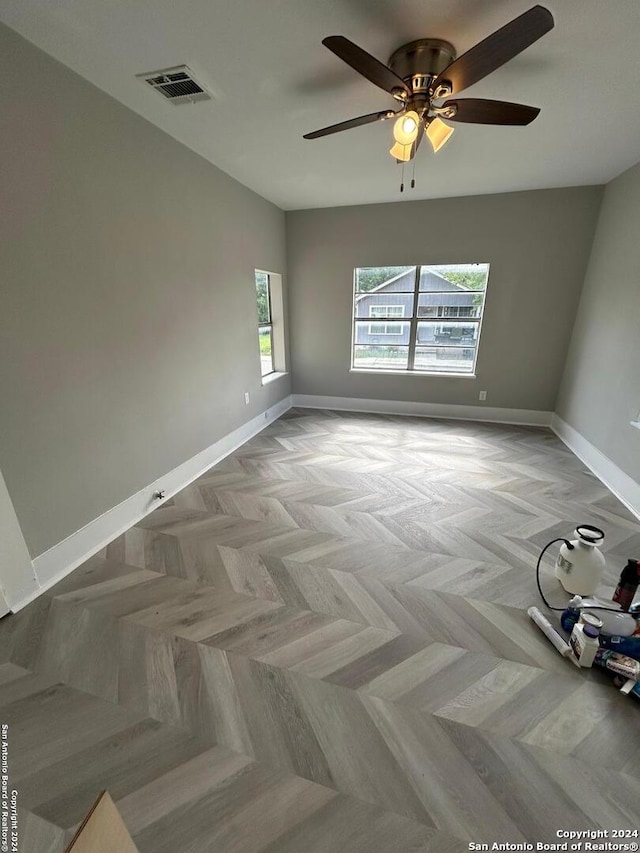 empty room with light parquet floors and ceiling fan