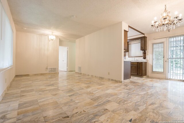 unfurnished living room with plenty of natural light, light tile patterned flooring, and a notable chandelier