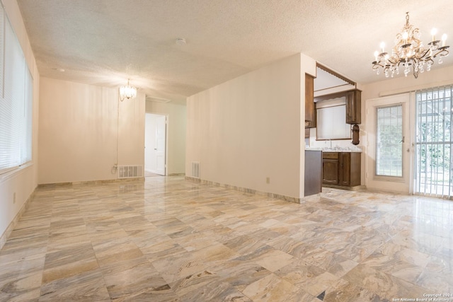 unfurnished living room with sink, a textured ceiling, and a chandelier